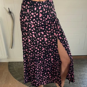 Svart och rosa mönstrad kjol från Zara - Säljer en superfin  långkjol från Zara med svart  rosa mönster. Kjolen har två slitsar fram som ger en extra touch. Perfekt för både vardag och fest! 🖤💖