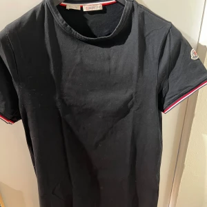 Moncler T-shirt - Den klassiska Moncler T-shirten med loggan på ärmen säljes nu i fint skick. Använd ett fåtal gånger. Skicket är 8/10. Passar storlek XS / S. Köpt på NK i Stockholm. 