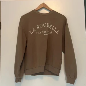 Brun tjocktröja - Nyskick och nästan aldrig använd. Vit text på framsidan. Strl xs från Gina tricot