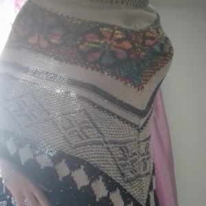 Mönstrad stickad poncho - Säljer en superfin stickad poncho med ett färgglatt mönster. Den har en mysig och varm känsla, perfekt för kyliga dagar. Mönstret är en mix av blommor och geometriska former i olika färger. Passar perfekt för höst och vinter!