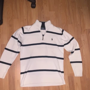 Vit/svart randig tröja från Ralph Lauren - Säljer en stilren vit tröja från Ralph Lauren med svarta ränder och zip halsen. Tröjan är i fint skick och passar dig som har storlek S-M och är perfekt för en avslappnad men snygg look. Nypris är jag osäker på men säljer denna för 400kr, tveka inte att höras av vid intresse😊