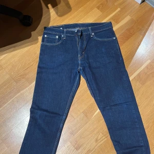 Levi's 512 jeans - Snygga Levi's 512 jeans i en klassisk blå färg. De har en straight passform med normal midja och är tillverkade i slitstarkt denim. Perfekta för en avslappnad stil med fem fickor och knappgylf.