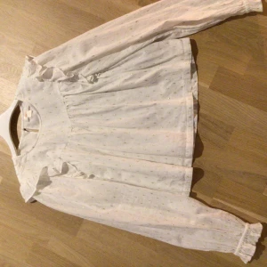 Blus - Vit blus med guld detaljer och volang. Använd 1 gång. Som ny. 