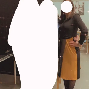 Klänning - Snygg klänning med svart överdel och gul och brun underdel. Den har trekvartsärmar och en figurnära passform som ger en stilren look. Perfekt för en kväll ute eller en speciell tillställning.