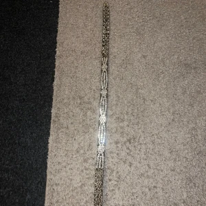 Leopardmönstrat bälte med strass - Snyggt leopardmönstrat bälte med glittrande strassdetaljer. Perfekt för att ge din outfit en extra touch. Bältet har en rektangulär spänne dekorerat med strass för extra bling. 