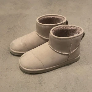 Liknande uggs - Säljer ett par bekväma beige boots med mjukt foder. Perfekta för kyliga dagar med sin varma insida och stilrena design. De har en rund tå och en stabil sula för bra grepp. Använt 1 gång!!!
