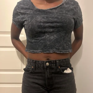 Basis Svart croppad t-shirt - Snygg svart croppad t-shirt med korta ärmar och en tvättad look. Perfekt för en avslappnad stil.