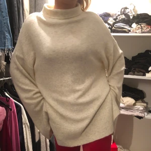 Beige stickad polotröja - Mysig beige stickad polotröja med en avslappnad passform. Perfekt för kyliga dagar med sin höga krage och långa ärmar. En stilren och bekväm tröja för alla tillfällen.