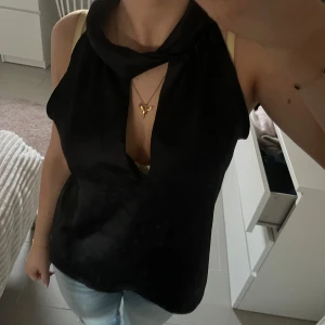 Svart ärmlös festtopp från Zara - Snygg svart ärmlös topp med djup v-ringning och hög krage. Perfekt till fest, passar till både kjol och jeans. Storlek S men skulle säga att den passar XS-M.