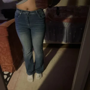 Blå bootcut jeans med broderi - Snygga blå bootcut jeans med ett unikt broderi på bakfickan. Perfekta för en avslappnad stil med en touch av detaljer. De har en klassisk femficksdesign och en bekväm passform. Dock lite hödmidjade.