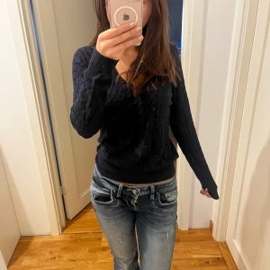 Svart stickad tröja - Säljer en svart stickad tröja med kabelstickat mönster. Tröjan har långa ärmar och en v-ringad hals. Pris kan diskuteras då den har några lösa trådar 