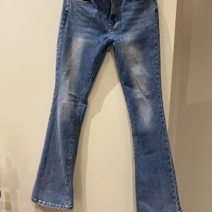 Blå bootcut jeans med broderade fickor - Snygga blå bootcut jeans med broderade detaljer på bakfickorna. De har en klassisk femficksdesign och en bekväm passform. Perfekta för en avslappnad stil.