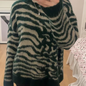 Mönstrad tröja - Säljer en cool och mysig tröja med grönt och beige zebramönster. Tröjan har långa ärmar och en avslappnad passform, perfekt för kyliga dagar. Den är både stilren och bekväm.