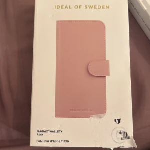 Rosa magnetisk plånbok från Ideal of Sweden - Snygg rosa magnetisk plånbok från Ideal of Sweden, designad för iPhone 11/XR. Den har flera kortfack och en praktisk magnetisk stängning. Perfekt för att hålla din telefon och kort på ett ställe.