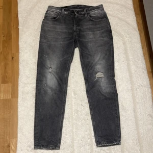 Svarta jeans från Dondup - Säljer ett par snygga svarta jeans från Dondup i modellen Brighton Carrot Fit.De har en cool slitning på knäna och en klassisk femficksdesign. Perfekta för en avslappnad men stilren look. Passar både till vardags och fest! Knappt använd så väldigt bra skick. Är intresserad av byte. Hör av dig vid frågor eller funderingar.