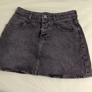 Grå jeanskjol som har aldrig använts  - Snygg grå jeanskjol med klassisk femficksdesign och knappgylf. Perfekt för en avslappnad stil. Och snygga personer!🔥🌟