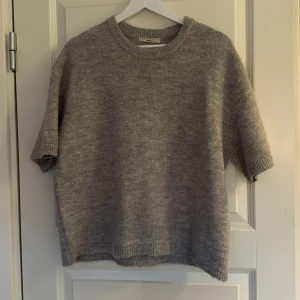 Grå stickad tröja från Gina Tricot - Mysig grå stickad tröja från Gina Tricot i premiumkvalitet. Tröjan har korta ärmar och en rund halsringning. Trekvartsärmad och så snygg!!💞🤩
