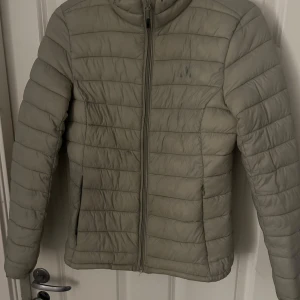 Beige pufferjacka från Whistler - Säljer en beige pufferjacka från Whistler med dragkedja framtill. Jackan har en quiltad design och är perfekt för kyligare väder. Den är stilren och funktionell, idealisk för både vardag och utomhusaktiviteter.inga defekter💕