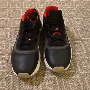 Svarta och röda sneakers - Snygga svarta sneakers med röda detaljer och vit sula. Perfekta för en sportig look. Skorna har snörning och en bekväm passform.