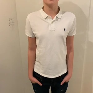 Vit kortärmad pikétröja från Ralph Lauren - Säljer en klassisk vit pikétröja från Ralph Lauren med korta ärmar och broderad logga på bröstet. Perfekt för en stilren look.