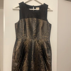 Klänning  - Snygg ärmlös klänning från hm med ormmönster i bruna och svarta toner. Den har en elegant plisserad svart överdel.