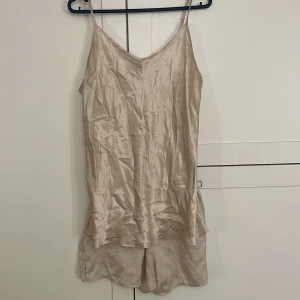 Beige sidenlinne och shorts från Intimissimi - Säljer ett beige pyjamas sätt i siden från Intimissimi, bestående av ett linne med smala axelband och matchande shorts. I storlek L. 🌟