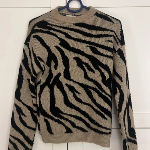 Beige och svart stickad tröja från ONLY  - Säljer en cool stickad tröja från ONLY med ett djärvt zebramönster i beige och svart.  Perfekt för att ge din outfit en trendig touch!