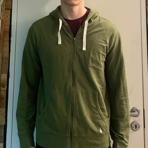 Grön zipper från Polo Ralph Lauren - Säljer en snygg grön zipper från Polo Ralph Lauren. Den har dragkedja och justerbara snören i huvan. Perfekt för en avslappnad stil. ASS snygg tycker jag själv knappt använd önskar jag kunde behåll men behöver pengar, basically ny skick😭inga missfärgningar, hål och slitmärken + väldigt skön, tipsar att köpa   Fett bra pris🙃