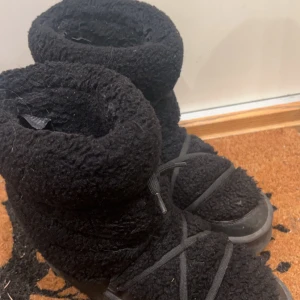 Svarta fluffiga vinterskor med snörning - Säljer ett par svarta vinterskor med snörning. De är täckta i ett fluffigt material som ger en mysig känsla. Perfekta för kalla dagar. Dom är i bra skick men har en skavank, se andra bilden.