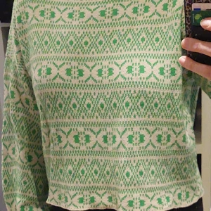 Grönmönstrad stickad tröja från ONLY - Säljer en snygg stickad tröja från ONLY i storlek L men är mer mot en stl M. Tröjan har ett grönt mönster på en vit bakgrund och långa ärmar. 