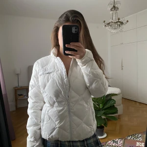 Vit pufferjacka - Säljer en snygg vit pufferjacka med dragkedja. Jackan har en quiltad design och långa ärmar, perfekt för kyligare dagar. Storlek M men skulle söga att den passar S lika bra 