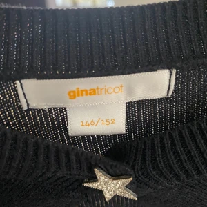 Marinblå kofta  - Snygg marinblå kofta från Gina Tricot med en glittrig stjärndetalj framtill. Storlek är 146/152 men funkar som XS. Tröjan har långa ärmar och volangdetaljer nedanför axlarna, vilket ger en trendig look. Perfekt för att piffa upp vardagsstilen!