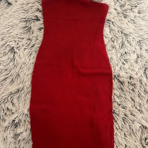 Röd ribbad klänning från H&M - Snygg röd ribbad klänning från H&M med en tight passform. Perfekt för en stilren look. Klänningen är axelbandslös och har en enkel design som gör den lätt att matcha med olika accessoarer.