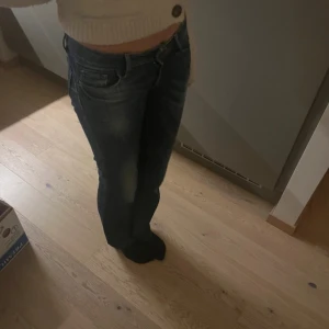 Mörkblå bootcut jeans - Snygga mörkblå bootcut jeans med en klassisk femficksdesign. Jeansen har en lågmidjad passform och är perfekta för en avslappnad stil. De har en lätt slitning på låren för en trendig look.