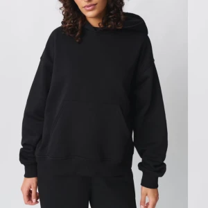 Svart hoodie från Gina tricot  - Säljer en klassisk svart hoodie i mjukt material. Perfekt för en avslappnad stil eller mysiga dagar hemma. Den har en rymlig passform och långa ärmar med ribbade muddar. Ett måste i garderoben för alla säsonger! 
