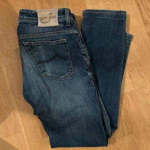 Blå jeans från Jacob Cohën - Säljer ett par snygga blå jeans från Jacob Cohën i storlek 33. De har en klassisk slim fit och är i mycket bra skick. Perfekta för både vardag och fest! 🕺