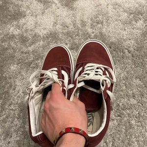 Vinröda sneakers från Vans - Säljer ett par snygga vinröda Vans sneakers i bra skick. De har klassisk vit snörning och den ikoniska vita sidostripen. Perfekta för både vardag och fest! Storleken är 43!