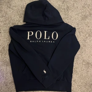 Mörkblå hoodie från Polo Ralph Lauren - Säljer en snygg mörkblå hoodie från Ralph Lauren. Den har en stor POLO-logga på framsidan och är perfekt för både höst och vinter. Materialet är mjukt och bekvämt. 