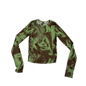 Grön och brun camouflage topp - Säljer en cool långärmad topp med camouflage-mönster i grönt och brunt. Perfekt för en avslappnad stil eller för att sticka ut lite extra. Toppen är i bra skick och passar perfekt till jeans eller kjol. Skön och lätt att bära!