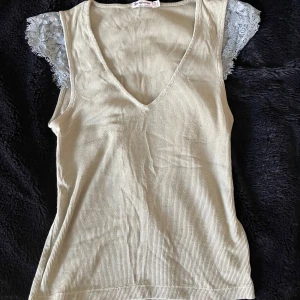 Grön topp Stradivarius - Säljer en grön ribbad topp från Stradivarius. Den har en v-ringad design och spetsdetaljer på ärmarna. Köpt i Frankrike