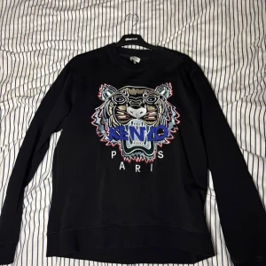 Svart sweatshirt från Kenzo - Säljer en svart sweatshirt från Kenzo. Tröjan är köpt på NK men kvittot finns inte kvar längre. Den är i storlek Medium och är i mycket bra skick. Priset är inte hugget i sten