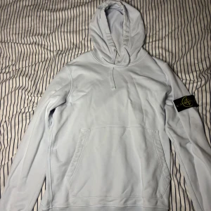 Ljusblå hoodie från Stone Island - Säljer en snygg ljusblå/babyblå hoodie från Stone Island. Den är i storlek Medium och är i fint skick förutom i bak då det finns ett hål, men syns inte när luvan är över och såklart så är den äkta