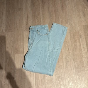 Ljusblå jeansbyxor - Säljer ett par ljusblå jeansbyxor i bra skick. De har en klassisk femficksdesign och knappgylf. Perfekta för vardagsbruk och kan matchas med nästan vad som helst. Passar både vår och sommar!