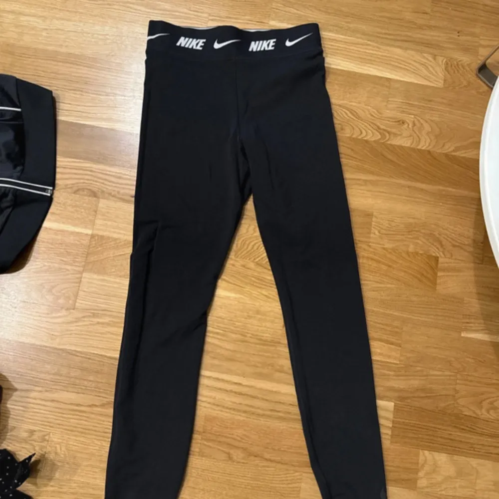 Säljer ett par svarta leggings från Nike i mycket bra skick. De är högmidjade med en elastisk midja som har Nike-loggan runtom. Perfekta för träning eller en chill dag hemma. Materialet är mjukt och stretchigt för bästa komfort.. Jeans & Byxor.