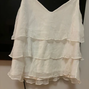 Vit volangtopp från Vero Moda - Säljer en superfin vit volangtopp från  Moda. Den är perfekt för vardag och speciellare event. Den är Xl o är liten i stlk så skulle säga passform är L. 