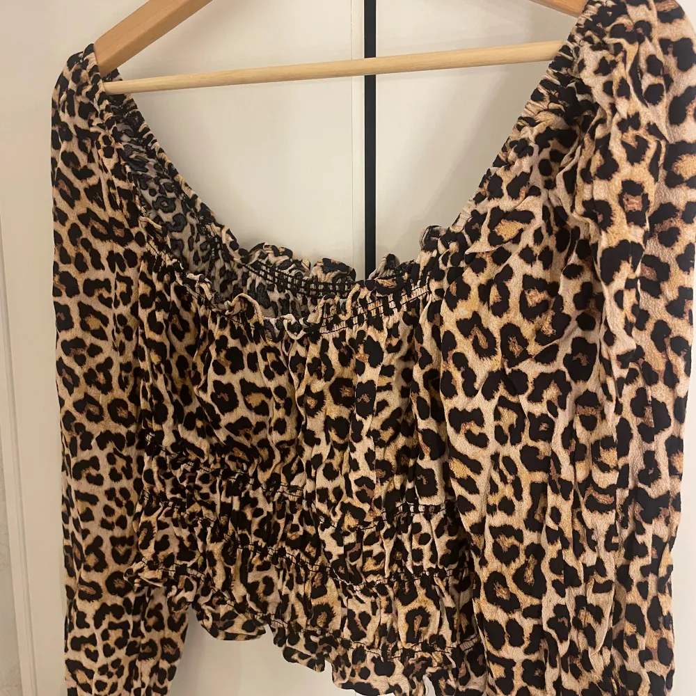 Säljer en superfin leopardmönstrad offshoulder topp från H&M. Den har en elastisk smockdetalj vid midjan och ärmarna, vilket ger en snygg passform. Perfekt för en utekväll eller fest! 🐆✨. Toppar.