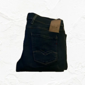 Mörkblå jeans från Replay - Säljer ett par snygga mörkblå jeans från Replay. De har en cool slitning på framsidan som ger en trendig look. Perfekta för både vardag och fest! . Slitningar är en del av modellen och ger en sjukt nice look på den tycker jag. Känner att jag inte vill ha dem längre så säljer dem. Frågor om mått, skriv dm.