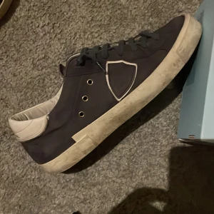 Mörkblå Philippe Model skor - Säljer ett par Philippe Model skor. Skorna är i bra skick med lite slitage på sulan, men fortfarande riktigt snygga. Det är storlek 41 men jag har 42 och de passar mig perfekt då de är stora i storleken 