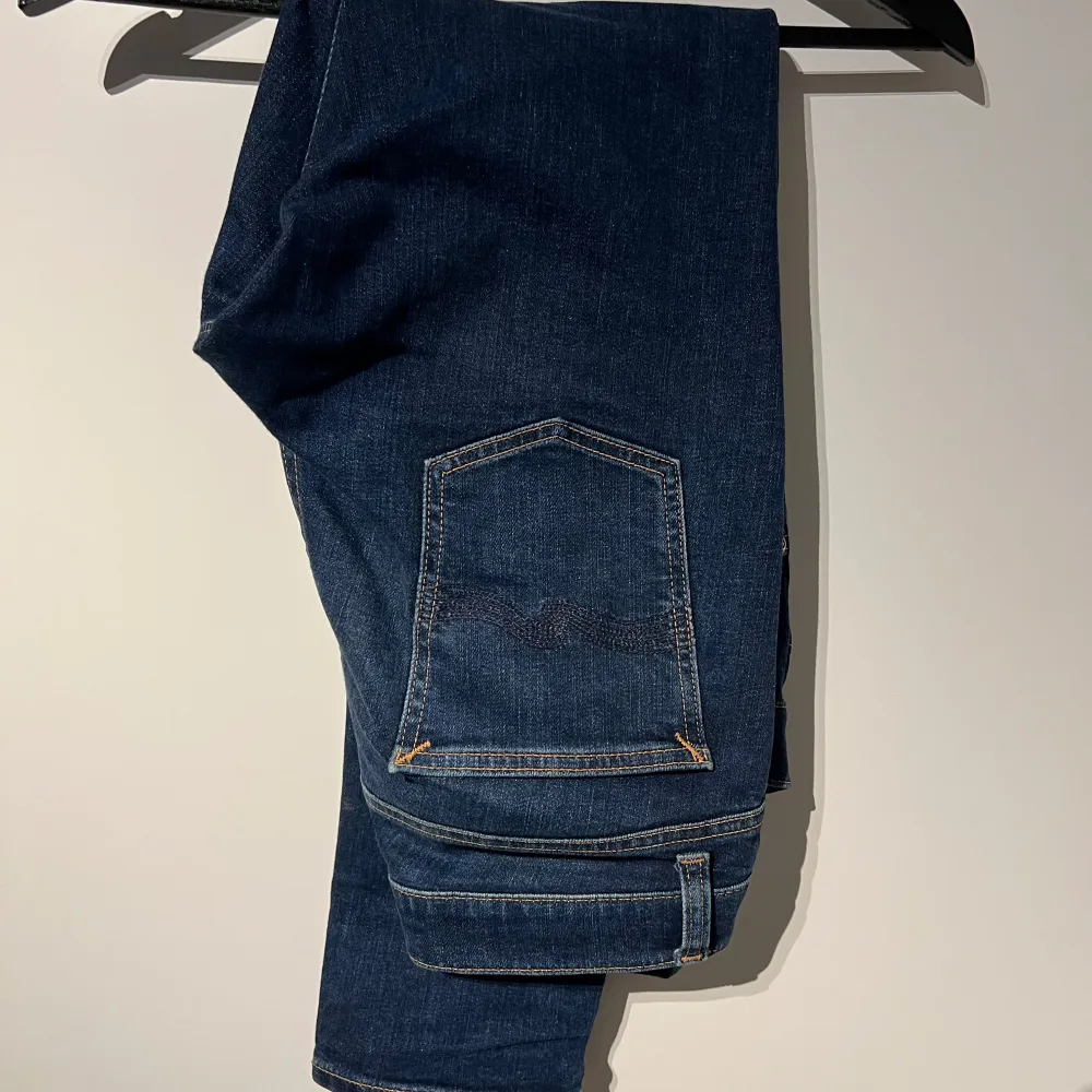 Säljer ett par mörkblå nudie jeans i bra skick. De har en slim fit. Klassisk design med fem fickor och knappgylf. Passar till det mesta och är superbekväma! Byxorna är näst intill nyskick och är i modellen tight terry storlek 32/30 personen på bilden är 183cm. Jeans & Byxor.