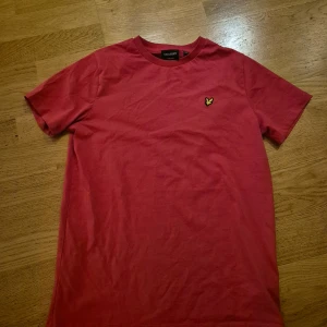 Röd t-shirt från Lyle & Scott - Säljer en snygg röd t-shirt från Lyle & Scott i storlek 14-15 år. Den har en klassisk passform med korta ärmar och ett litet broderat emblem på bröstet. Perfekt för vardagsbruk eller en avslappnad stil. 🛍️ Endast provad men passade inte mig.